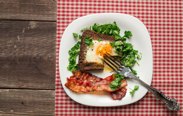 Fried egg in rye bread with bacon and parsley