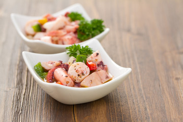 salad with octopus in bowl on wooden wooden background