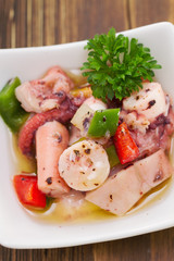 salad with octopus sea food on small white dish on brown wooden background