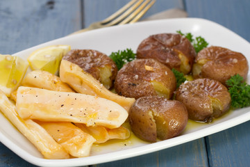 octopus with potato on white dish on blue wooden background