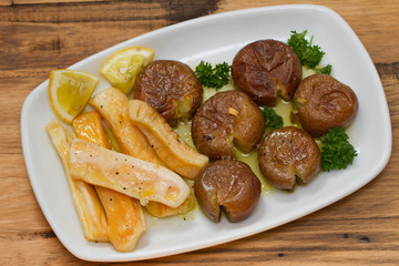 octopus with potato on white dish on brown wooden background