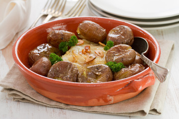 fish with potato in ceramic dish on white wooden background