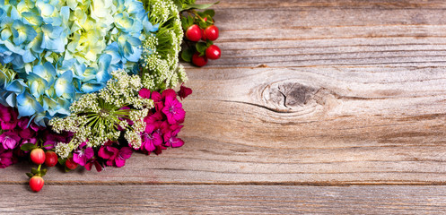 Colorful seasonal assorted flowers on stressed wood background