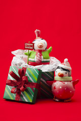 view of christmas gifts box and penguin toys over red background.