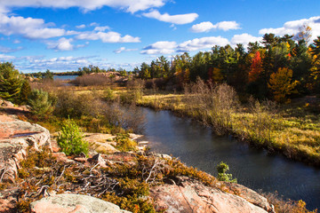 Obraz premium Autumn trees , red rocks and Chikanishing Creek in Killarney Provincial Park Ontario Canada 