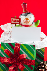 view of a snowman with empty placard and christmas gift box.