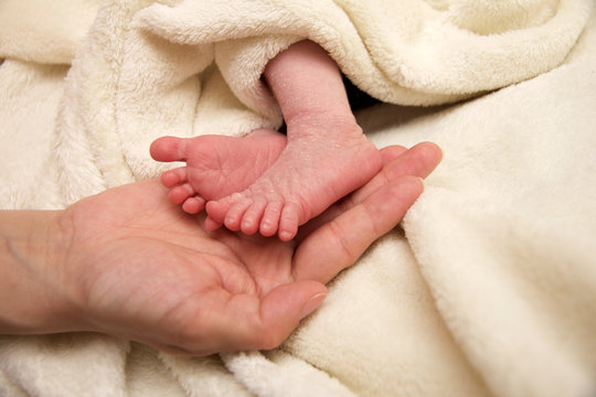 Süße Babyfüße mit schützender Hand von Mutter