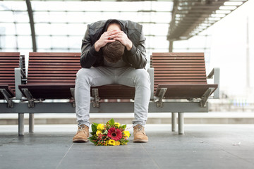 Einsamer Mann mit Blumenstrauß am Bahnsteig