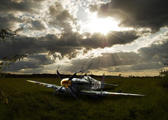 Crashed Spitfire in field with dramatic sunset WWII