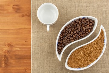Natural coffee beans versus instant. Soluble and coffee beans on wooden background. Preparing fresh coffee. Sales of roasted coffee. Advertising for the sale of coffee.
