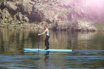 Fototapeta na wymiar slim athletic girl stand up paddle board SUP