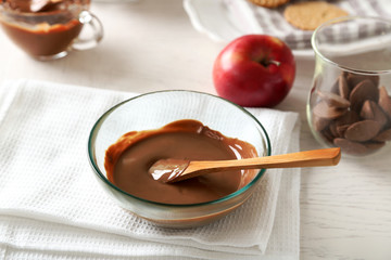Melted chocolate on glass bowl, on wooden background