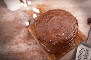 Chocolate cake with blade on a wooden boards background