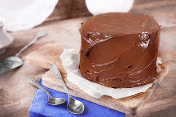 Chocolate cake with two spoons and blue tablecloth on a wooden boards background