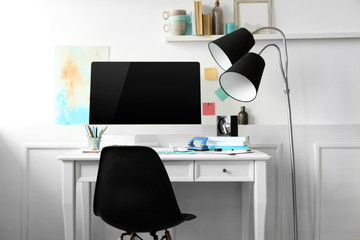 Modern wide screen monitor on white table and chair in room interior