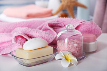 Fototapeta na wymiar Pink towel with salt and soap on bathroom table