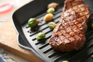 Grilled steak with garlic and Brussels sprouts on grill pan, closeup