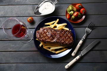 Grilled steak with french fries, glass of wine and vegetables, closeup