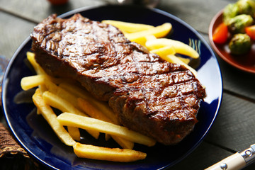 Grilled steak with french fries and vegetables, closeup