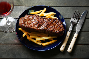 Grilled steak with french fries and glass of wine, closeup