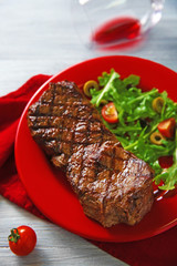 Grilled steak with vegetable salad and wine, closeup