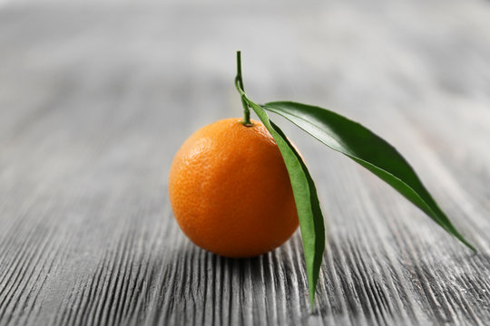 Fresh tangerines with leaves on wooden table, closeup