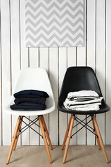 Stack of clothes on black and white chairs over wooden wall background