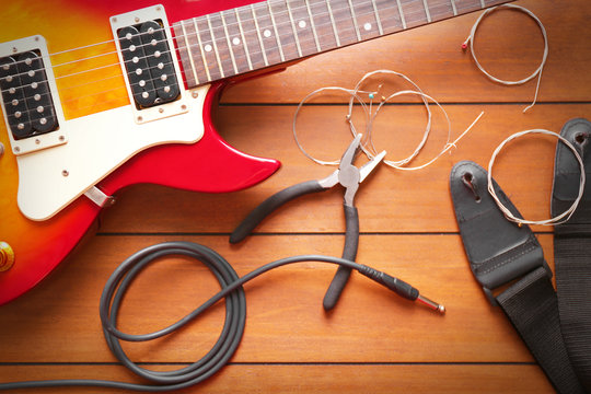 Electric guitar with pliers and strings on wooden background