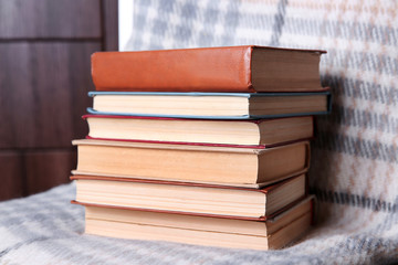 Stack of books with warm plaid on chair