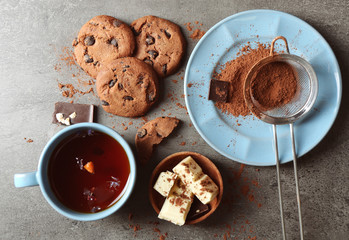 Chocolate chip cookies and a cup of tea on dark grey background