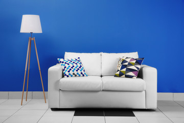 Comfortable white sofa on blue wall background