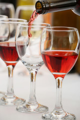 Red wine pouring into glasses, closeup