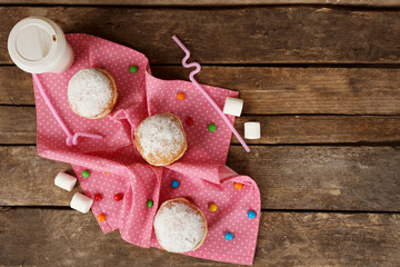 Delicious sugary donuts with pink napkin on wooden table, top view