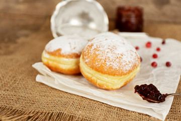 Delicious donuts with jam on parchment and sackcloth closeup