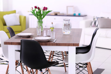 Modern living room. Furniture set with table and chairs. Bouquet of beautiful purple tulips on the table