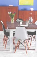 Modern living room. Furniture set with table and chairs. Bouquet of beautiful white and purple tulips on the table