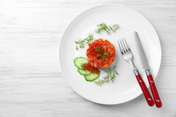 Delicious salmon tartare with red caviar on white plate