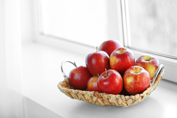 Naklejka na ściany i meble Ripe red apples in a wicker basket on windowsill