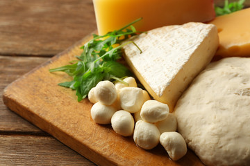 Fresh Italian pizza dough with different kinds of cheese on wooden background