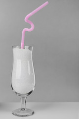 Hurricane glass with granulated sugar and cocktail straw on grey background