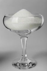 Margarita glass filled with granulated sugar on grey background