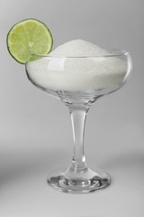 Margarita glass with granulated sugar and slice of lime on grey background
