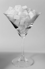Martini glass filled with lump sugar on grey background