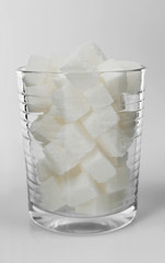 Old fashioned glass filled with lump sugar on grey background