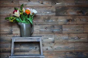 Fototapeta na wymiar A bouquet of fresh flowers in a watering can on wooden background