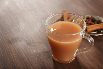 Milk tea with spices on wooden background.