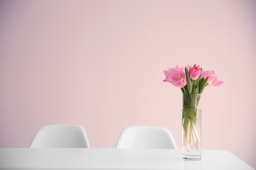 Beautiful tulips on dinning table against white wall background
