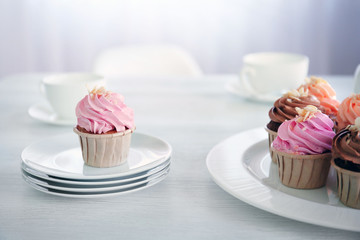 Creamy cupcakes and tea on table indoors
