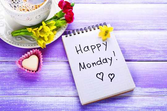Cup of coffee, chocolate candy, flowers and note HAPPY MONDAY on wooden background