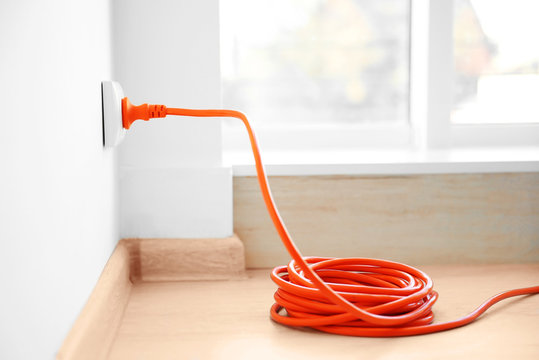 Orange extension into power outlet indoors